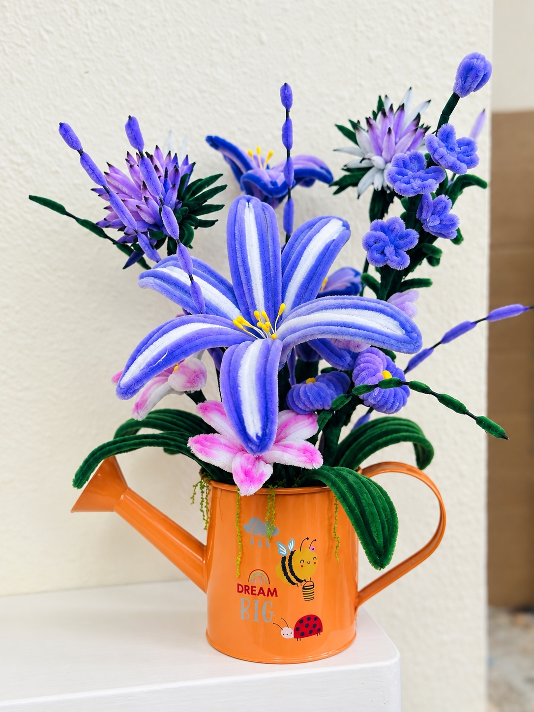 Purple blooms in a watering can — handcrafted flower arrangement