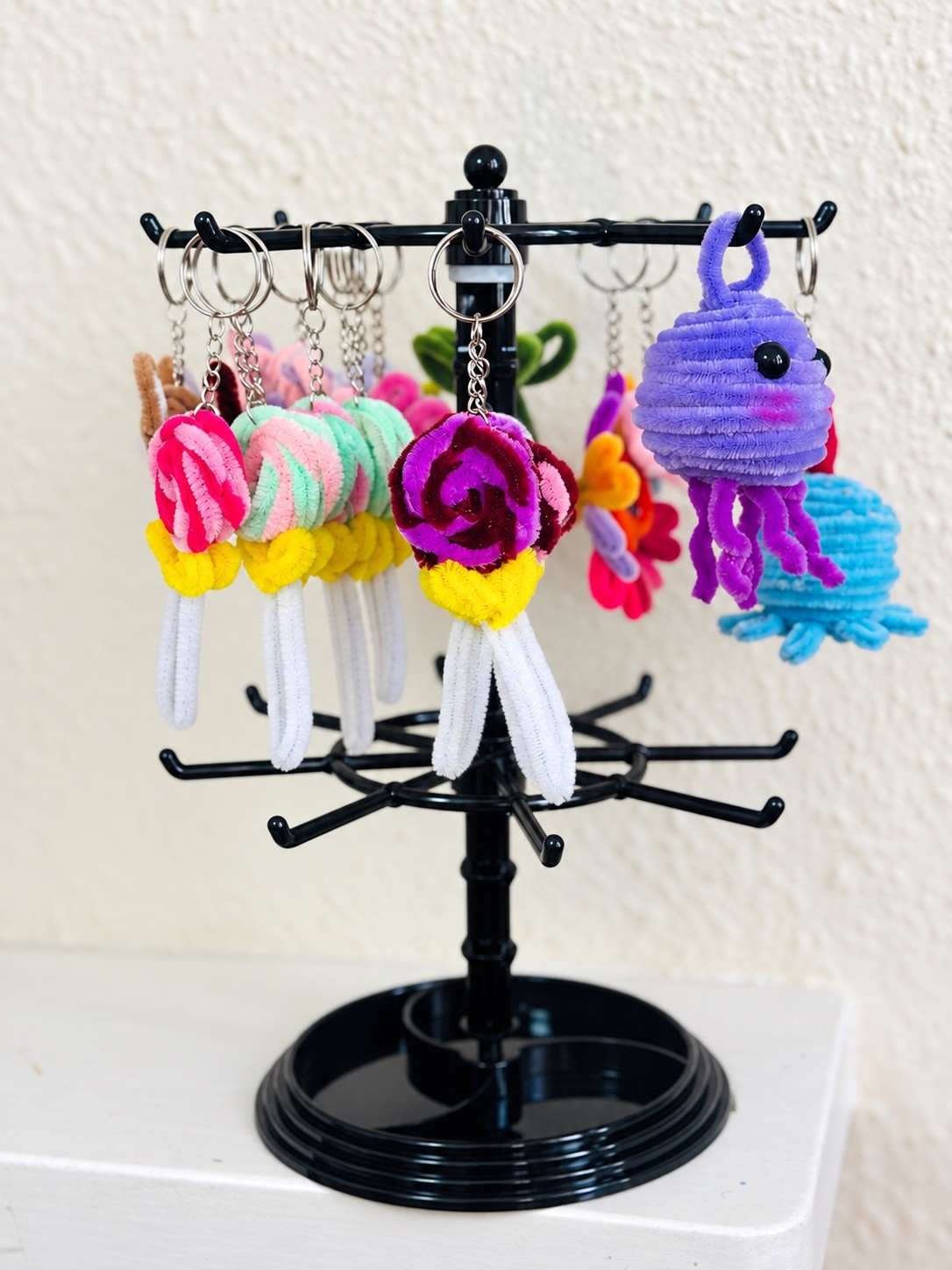 Handcrafted pink and pastel rose keyrings with purple and blue jellyfish charms on a display stand