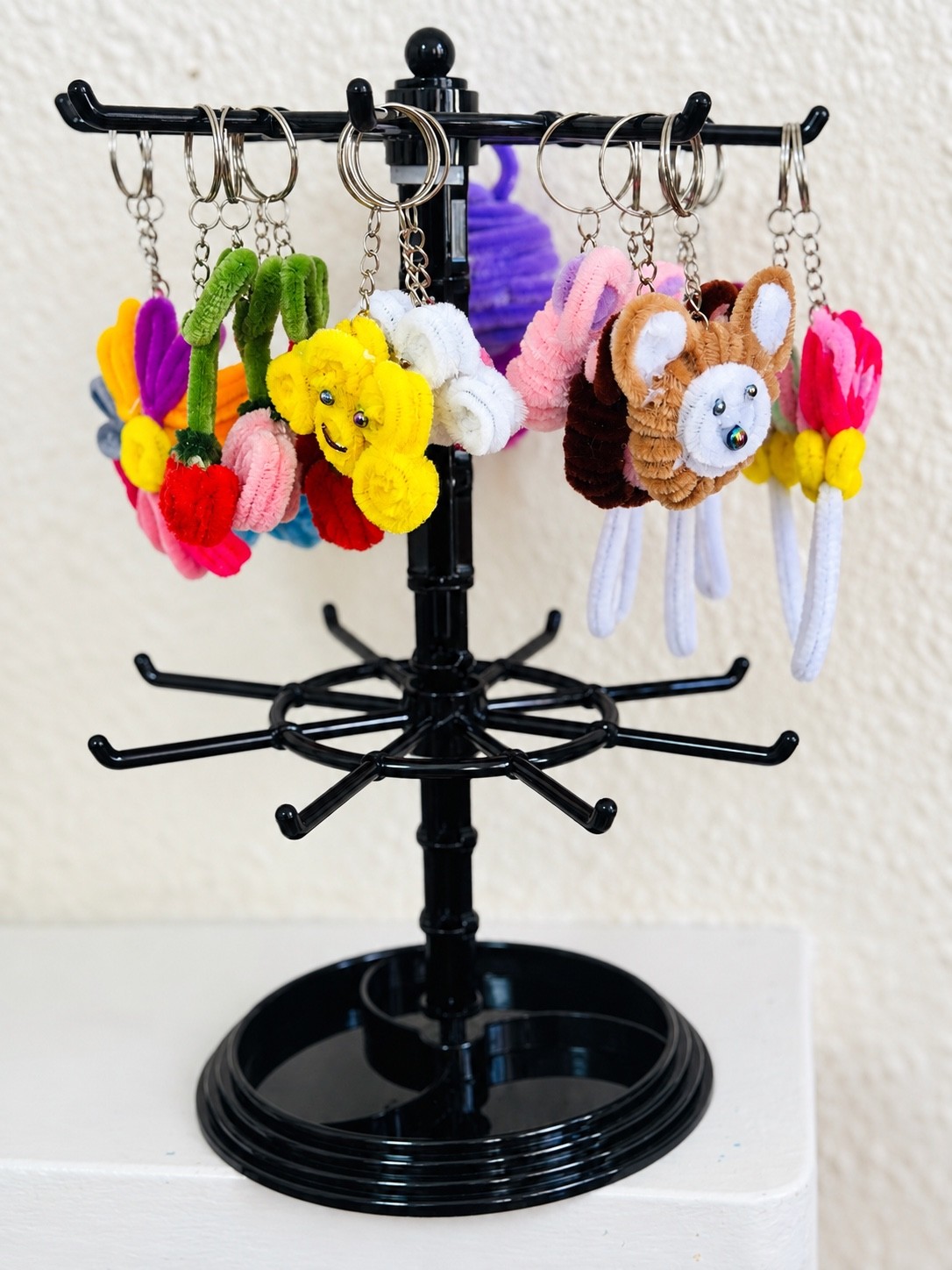 Handmade cherry, smiling flower and brown animal keyrings on a display stand