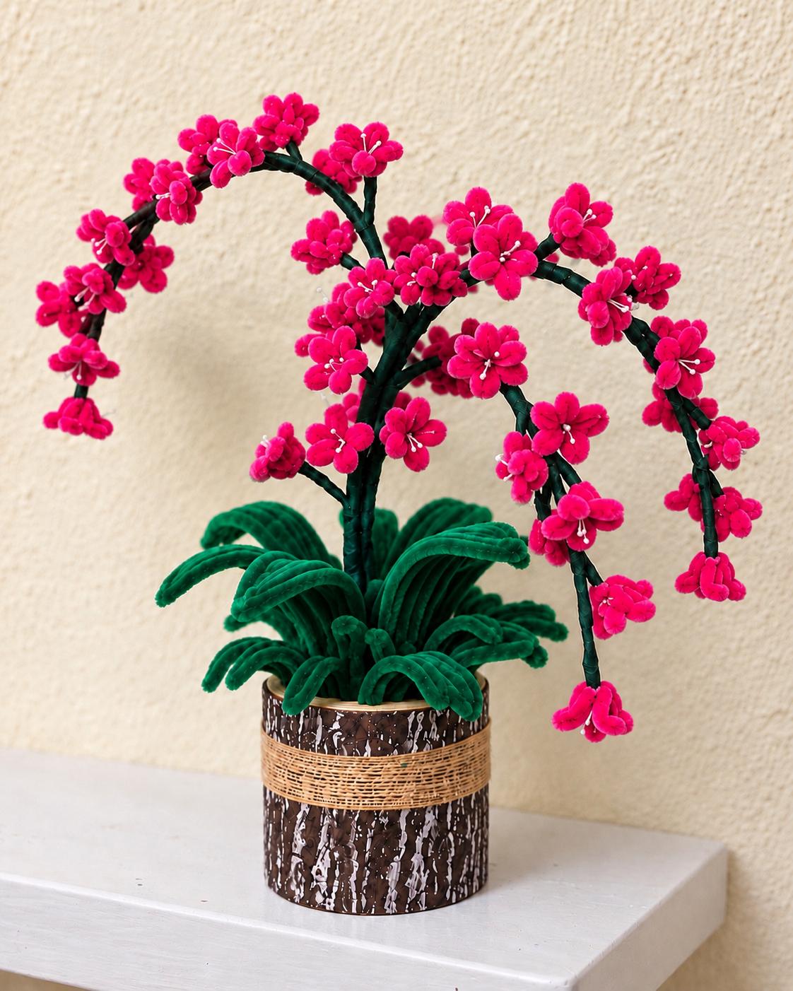 Pink handcrafted blossom arrangement with arching branches and green leaves in a rustic brown pot
